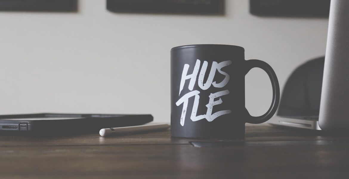 black and white Hustle-printed ceramic mug on table