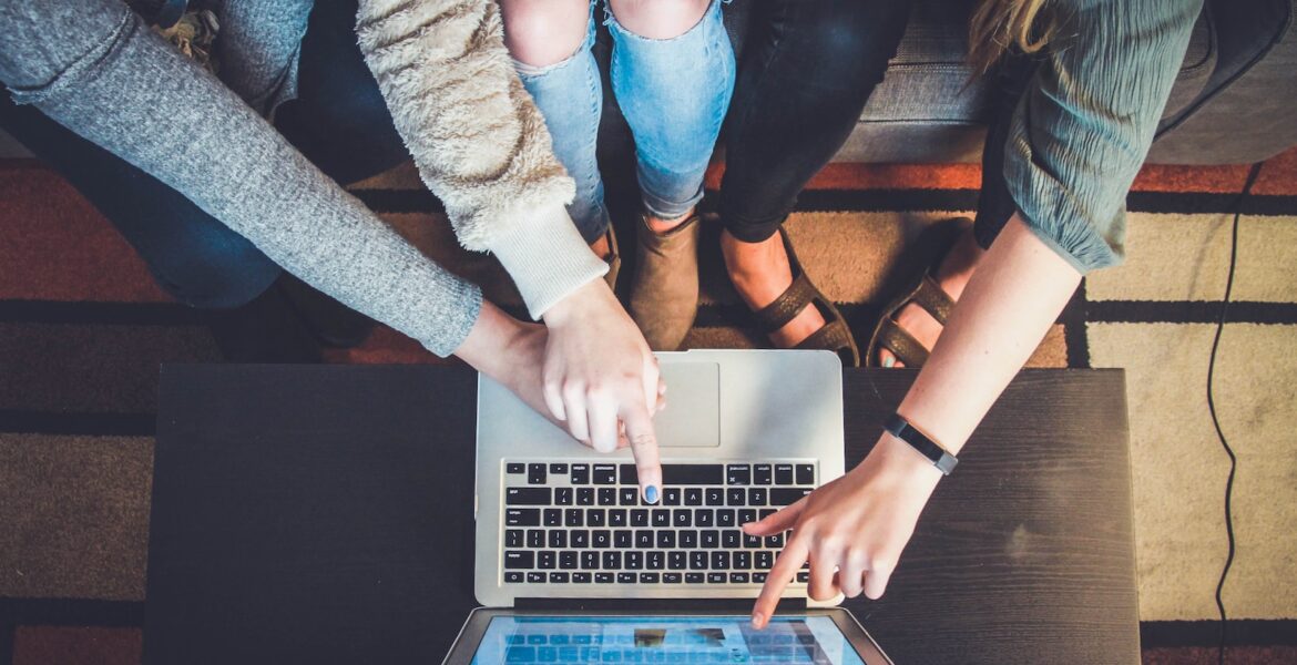 three person pointing the silver laptop computer