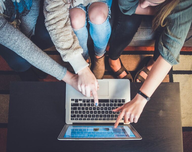 three person pointing the silver laptop computer