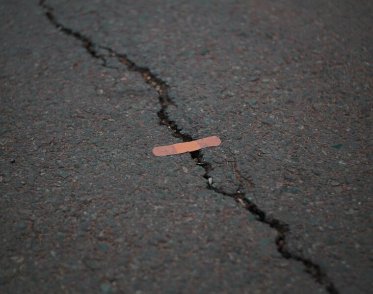 orange band aid on concrete surface crack